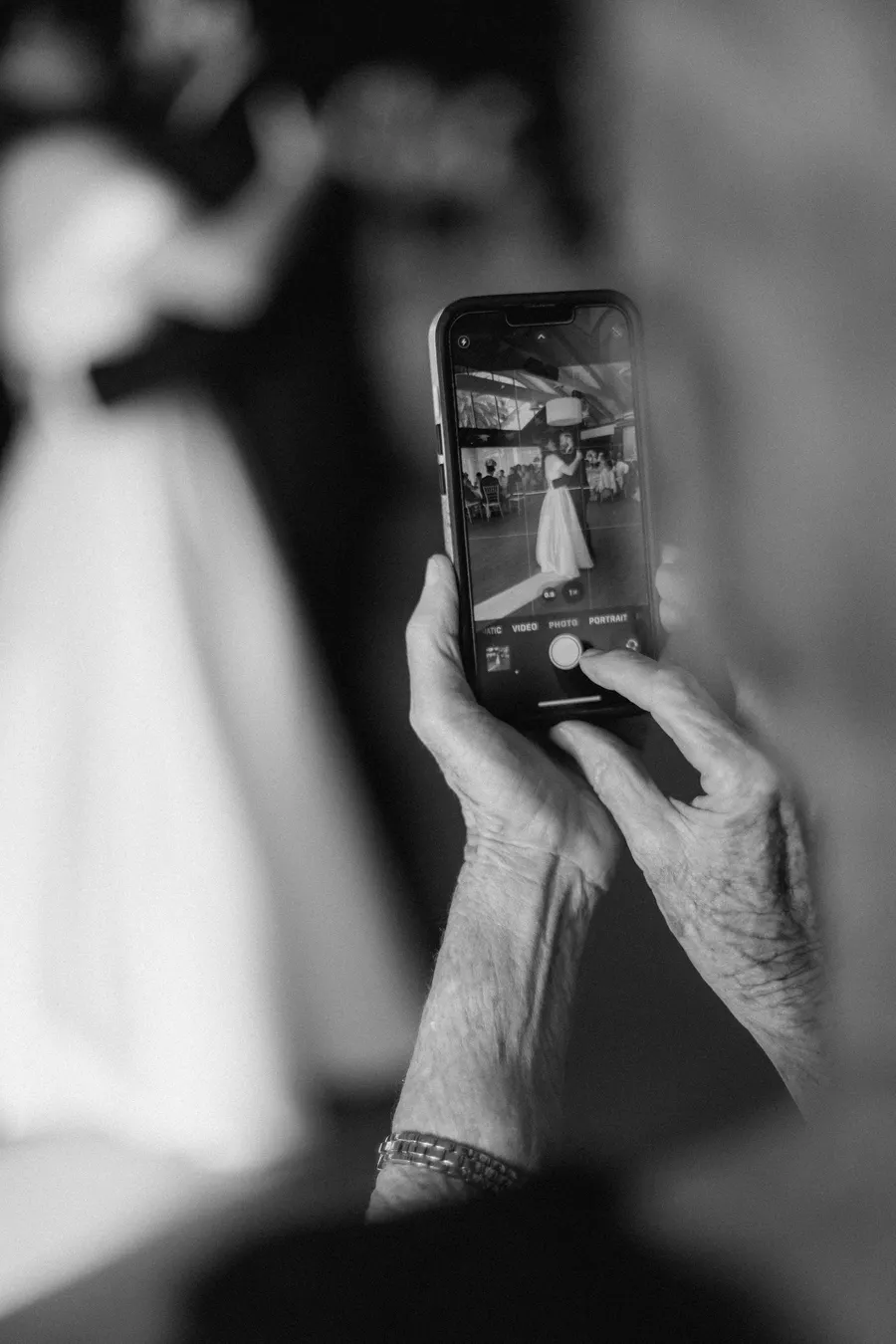 Black-and-white detail of a bride adjusting an earring