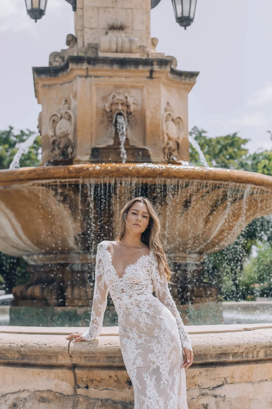 Bride posing beside an ornate fountain in a destination city