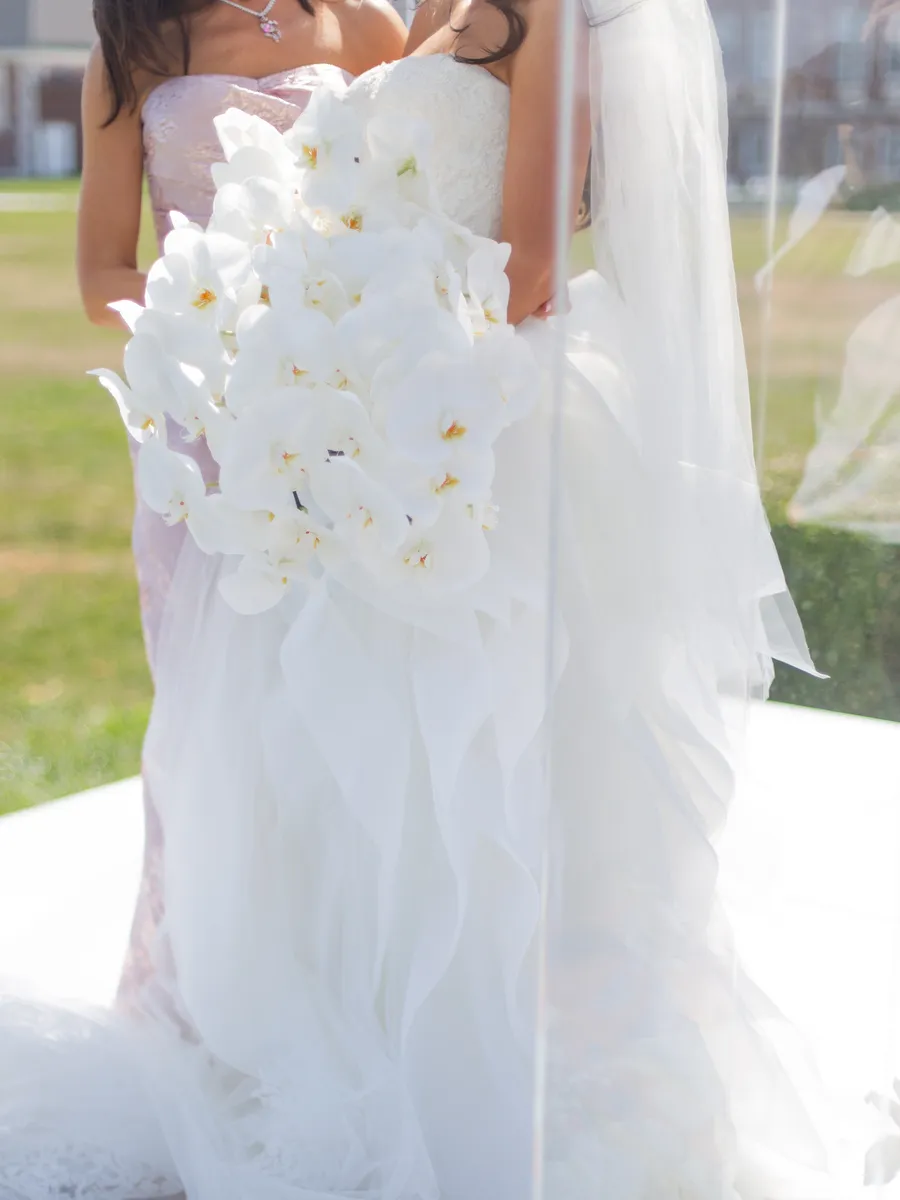 Groom waiting beneath the wedding ceremony flowers — David and Katia wedding