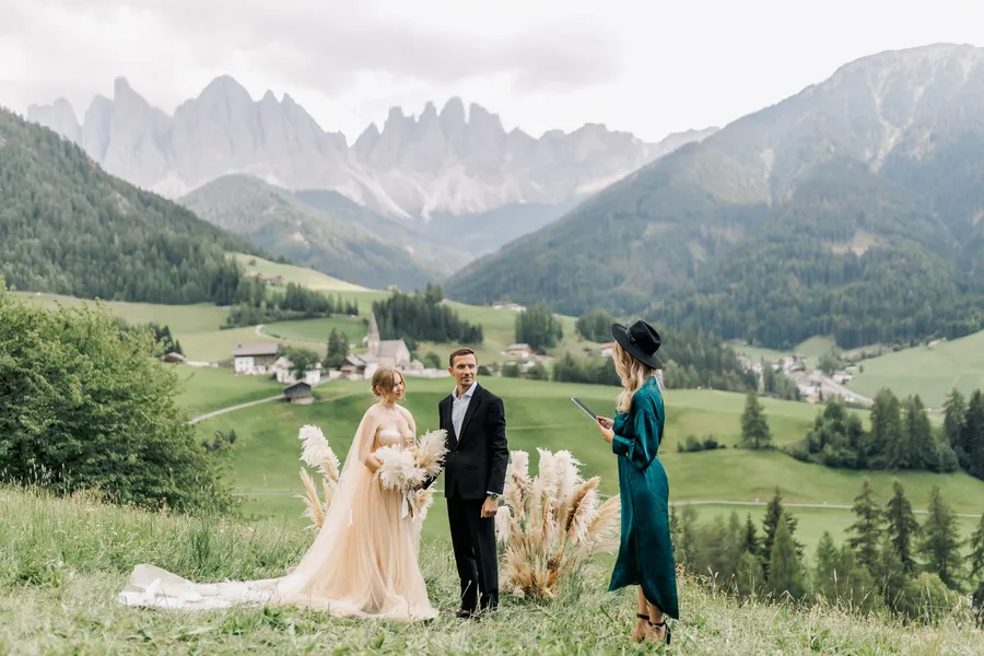 Wedding couple and guest walking through an alpine landscape