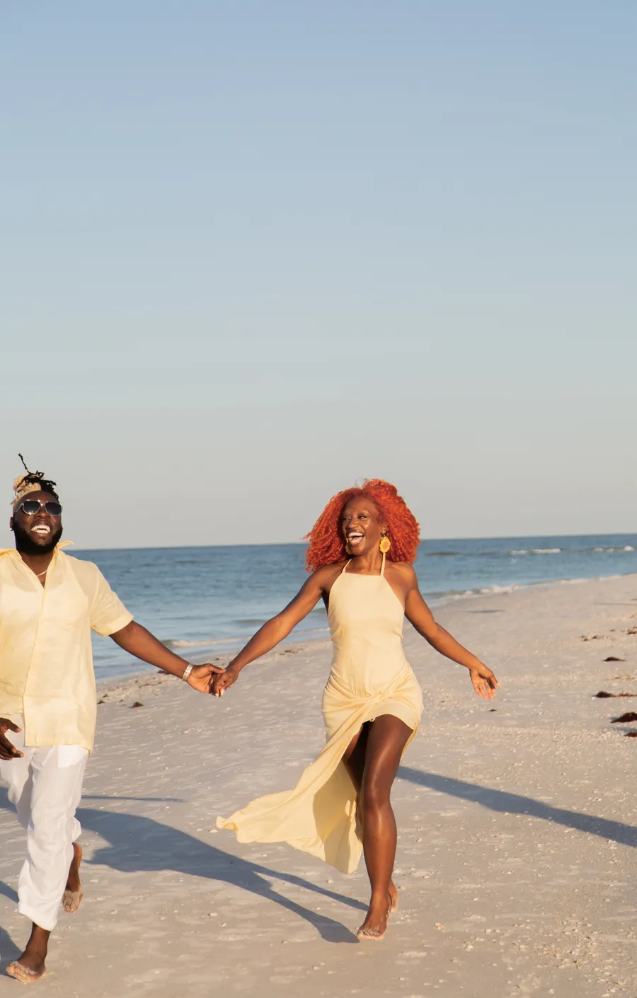Couple holding hands and running along the sand