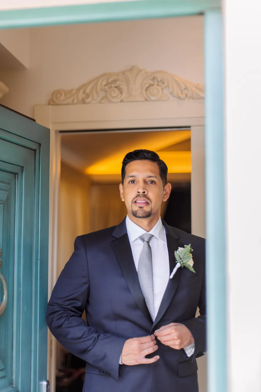 Groom in a navy suit standing in a colorful doorway