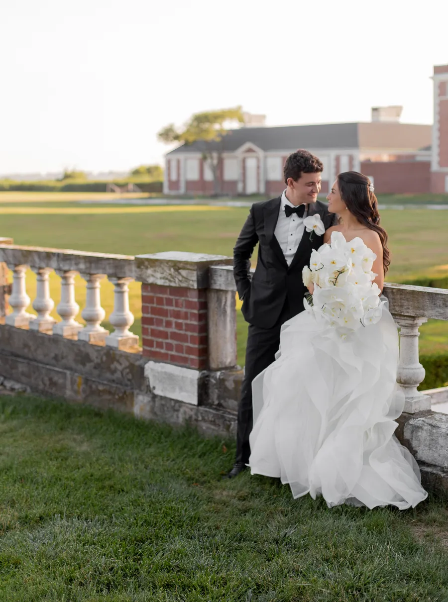 Bride and groom walking beside a brick estate after the ceremony