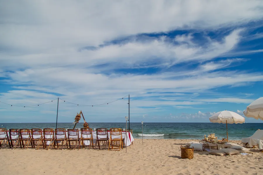Reception table and ceremony chairs arranged on the sand — Roman and Victoria wedding