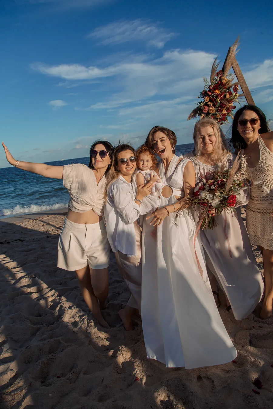 Newlyweds posing beneath a rustic beach ceremony arch — Roman and Victoria wedding