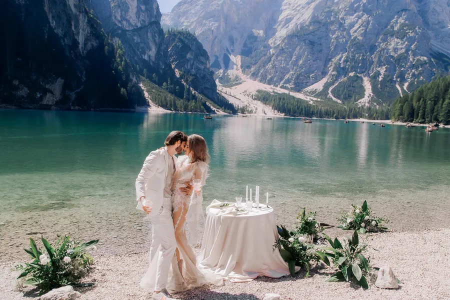 Newlyweds beside a turquoise mountain lake ceremony table