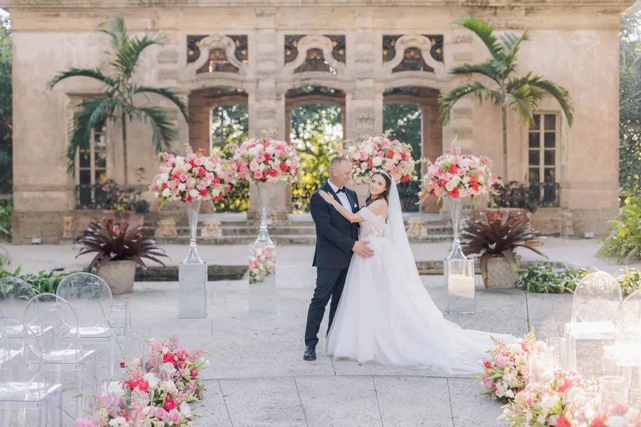 Bride and groom beneath abundant pink ceremony flowers — Steven and Iryna wedding