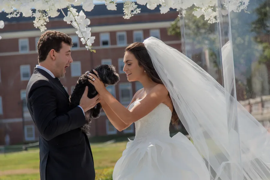 Groom waiting beneath the wedding ceremony flowers — David and Katia wedding