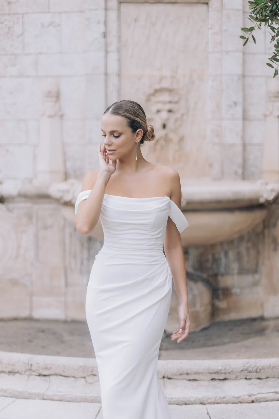 Bride in a modern gown beside pale stone architecture
