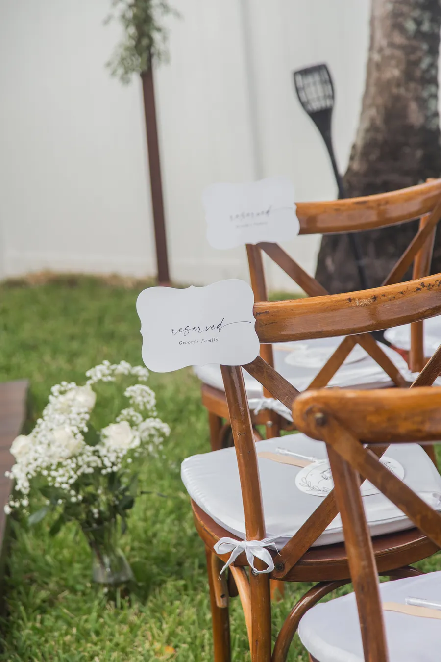 White floral ceremony arrangement beside wooden chairs — Chris and Laura wedding