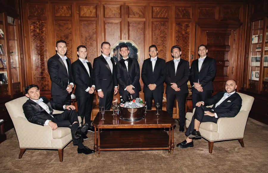 Groom and groomsmen posing in a wood-paneled library