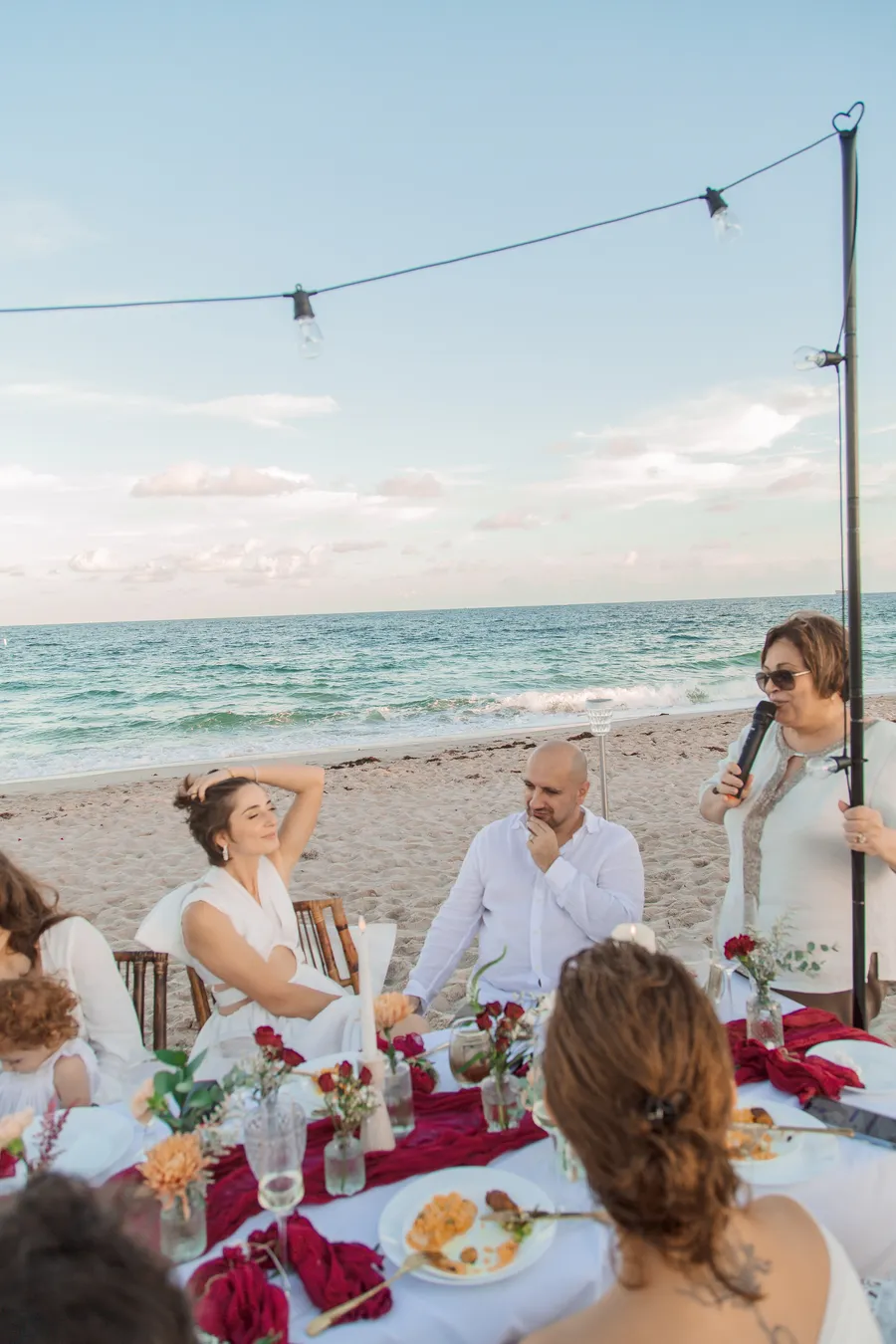 Bride holding a child during the beach reception — Roman and Victoria wedding