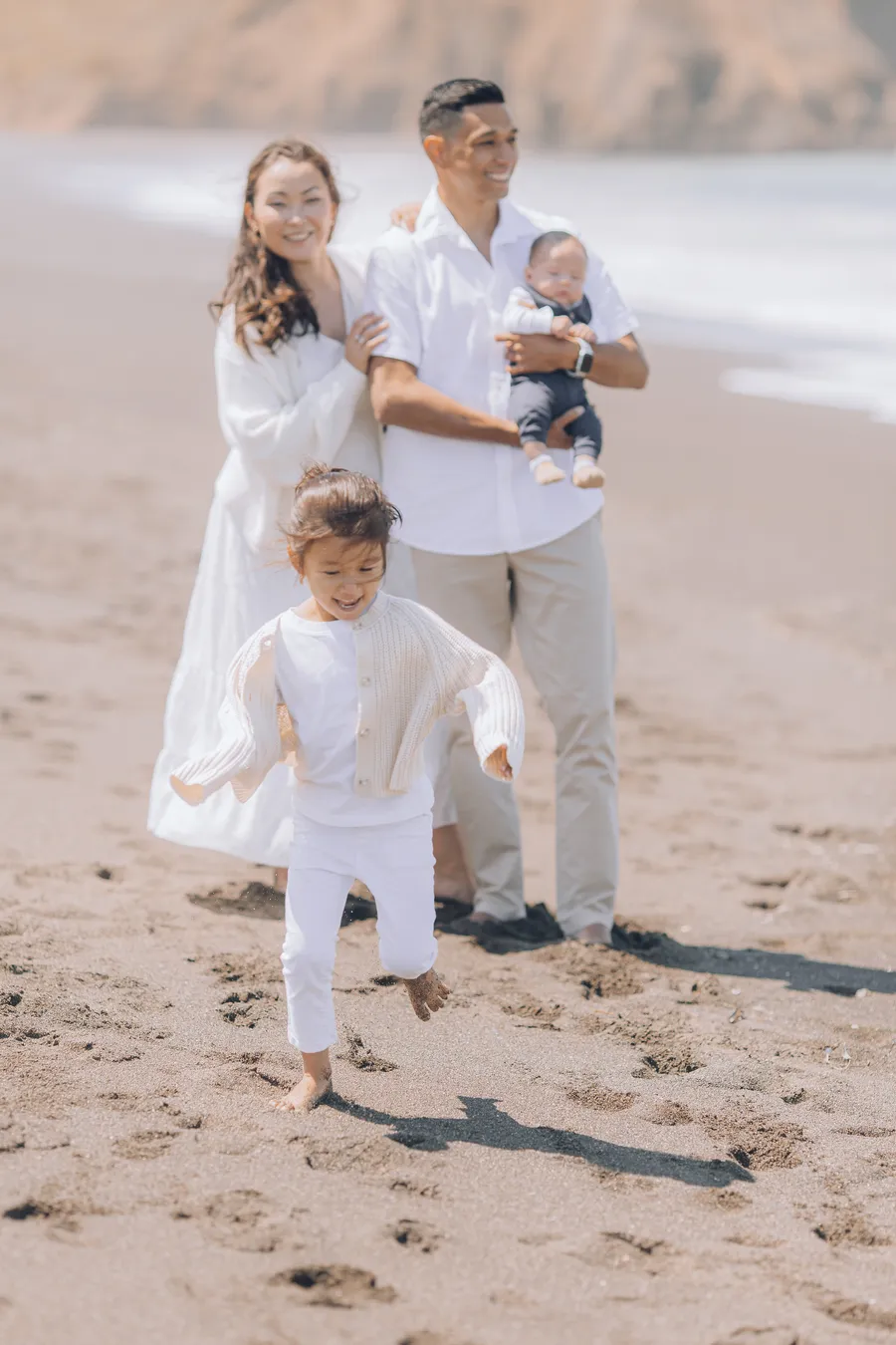 Parents walking with their baby along the beach