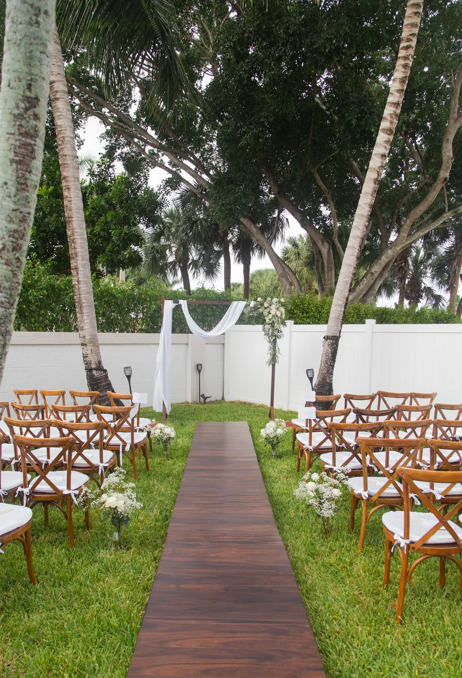 Outdoor ceremony aisle prepared beneath tropical trees — Chris and Laura wedding