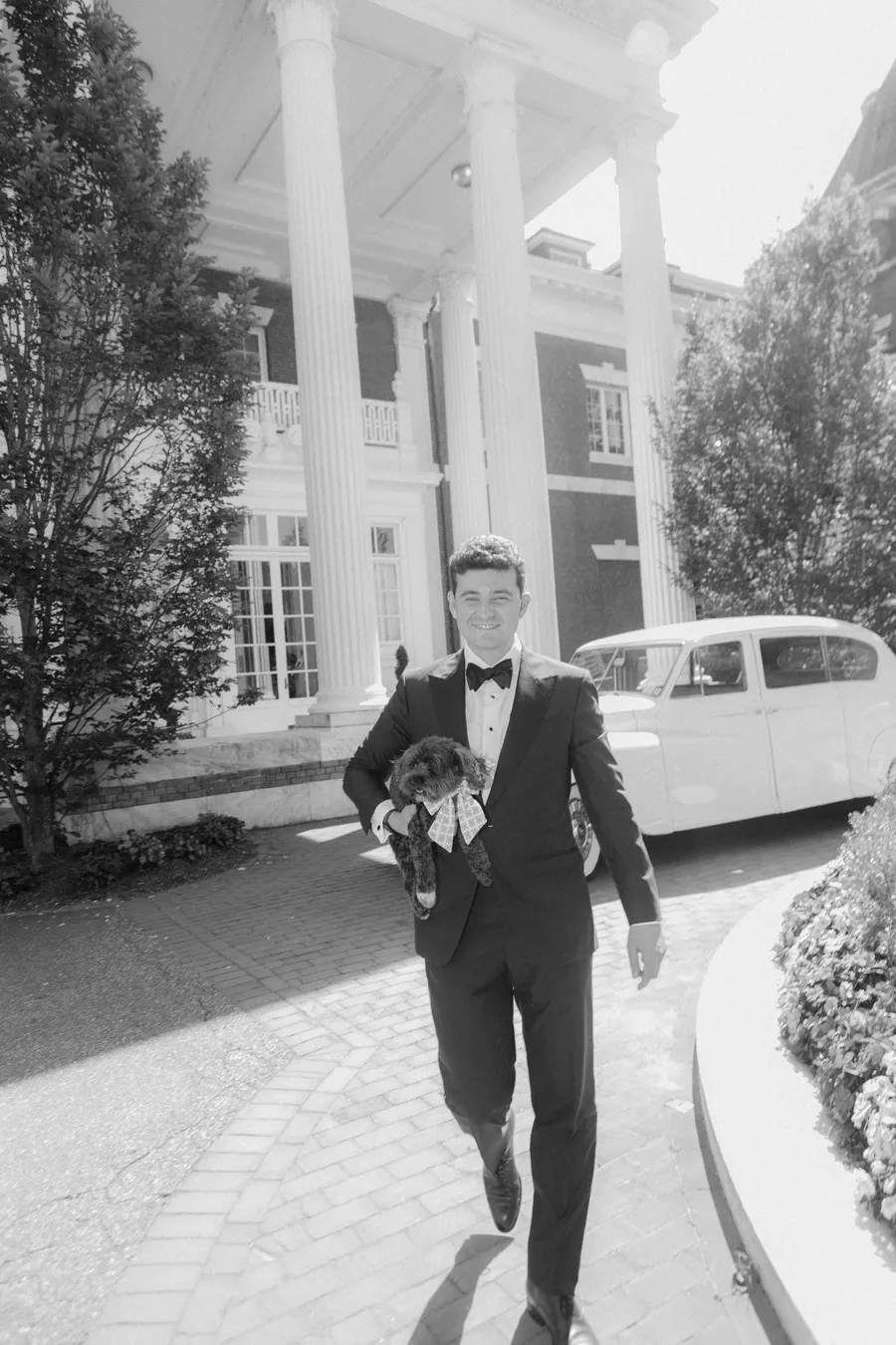 Black-and-white portrait of a groom walking outside