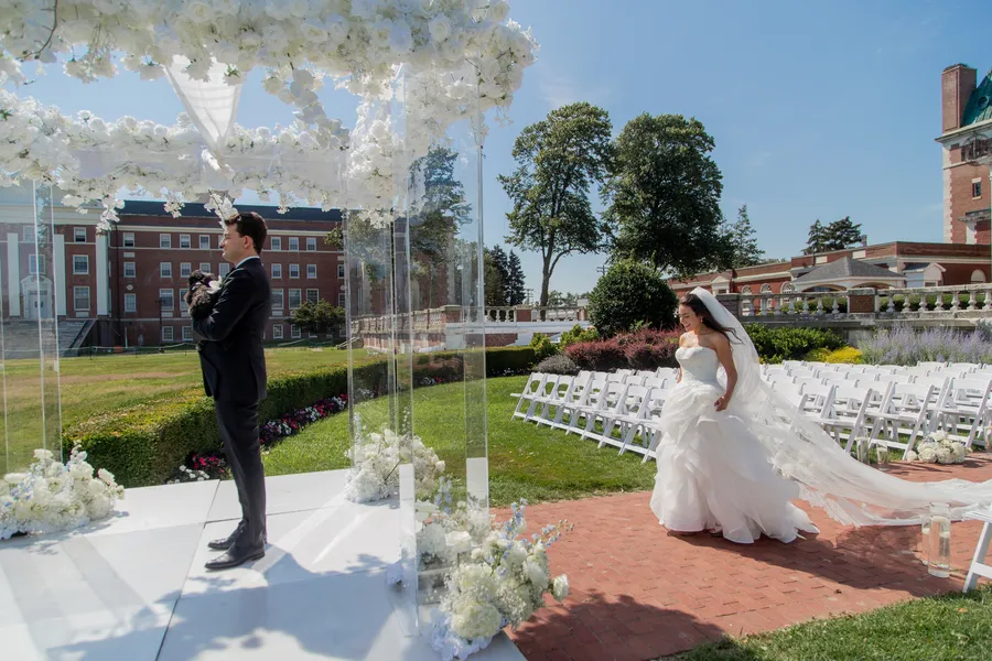 Groom waiting beneath the wedding ceremony flowers — David and Katia wedding