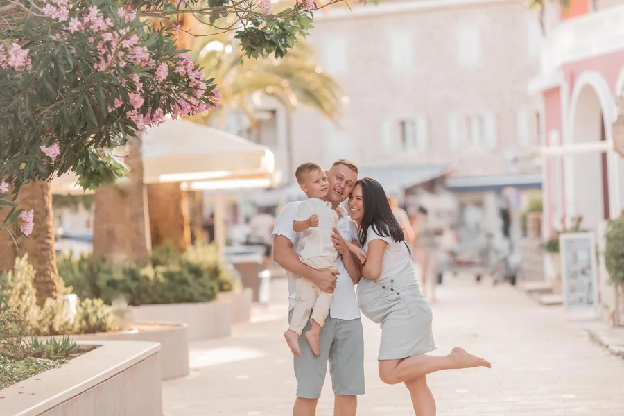 Parents playing with their child on a sunlit waterfront street