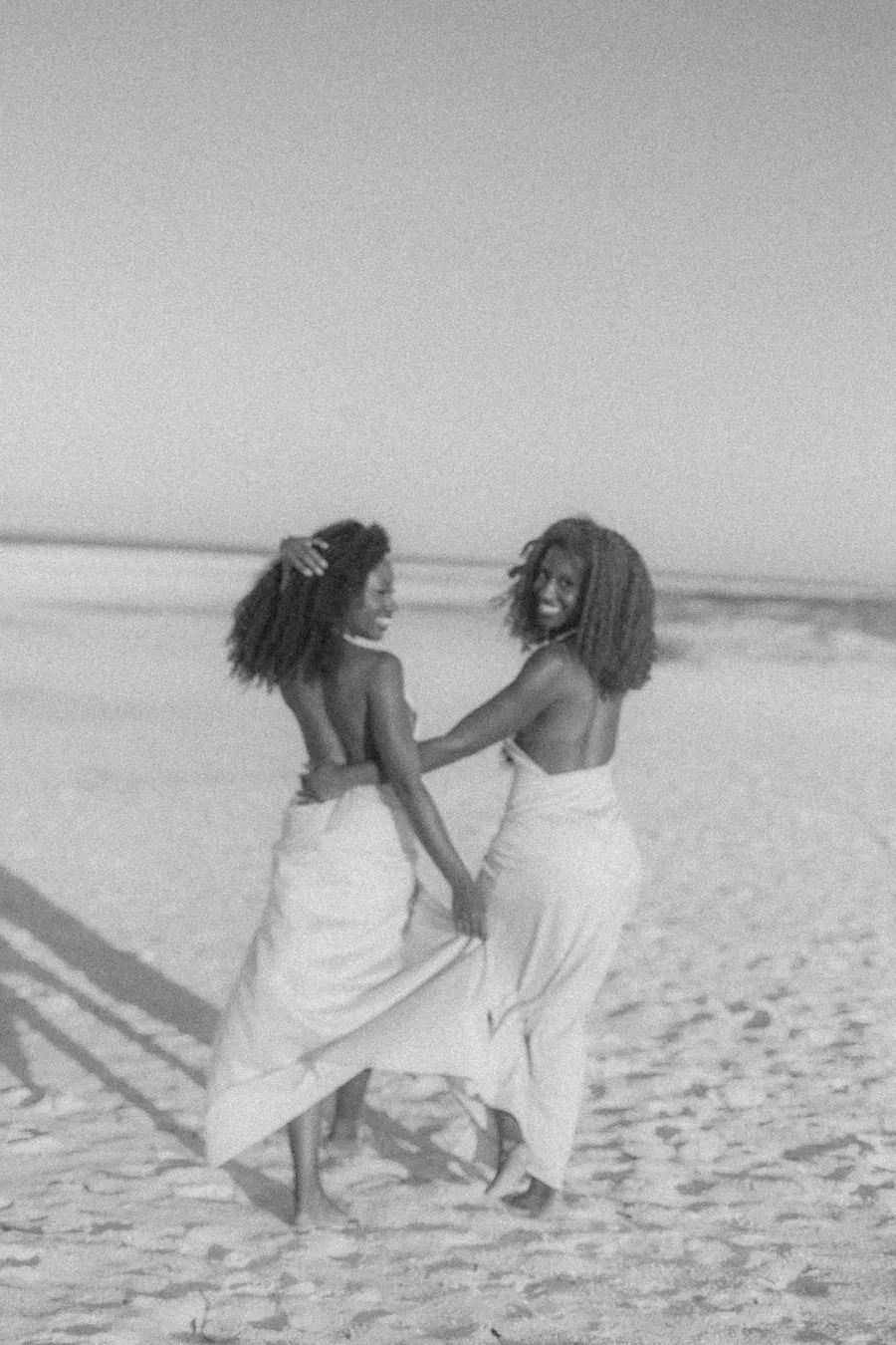 Black-and-white photograph of two women running along the shoreline