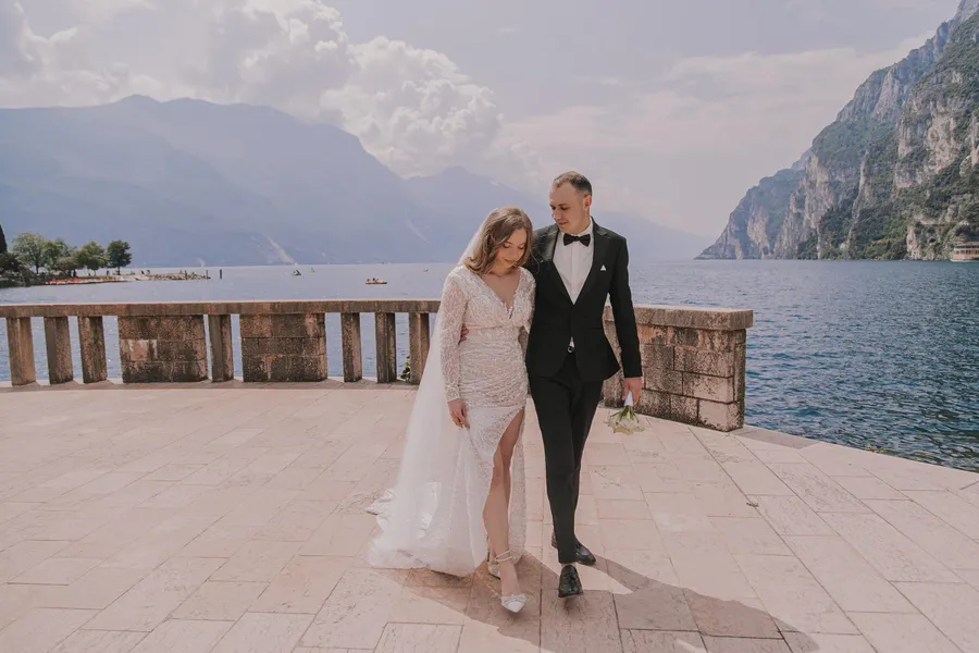 Bride and groom walking beside a lakeside stone terrace