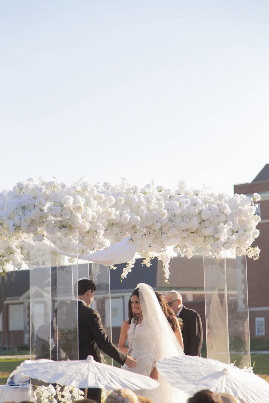 Bride and groom beneath a white floral arch — David and Katia wedding