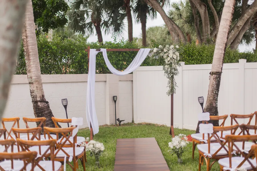 White floral ceremony arrangement beside wooden chairs — Chris and Laura wedding