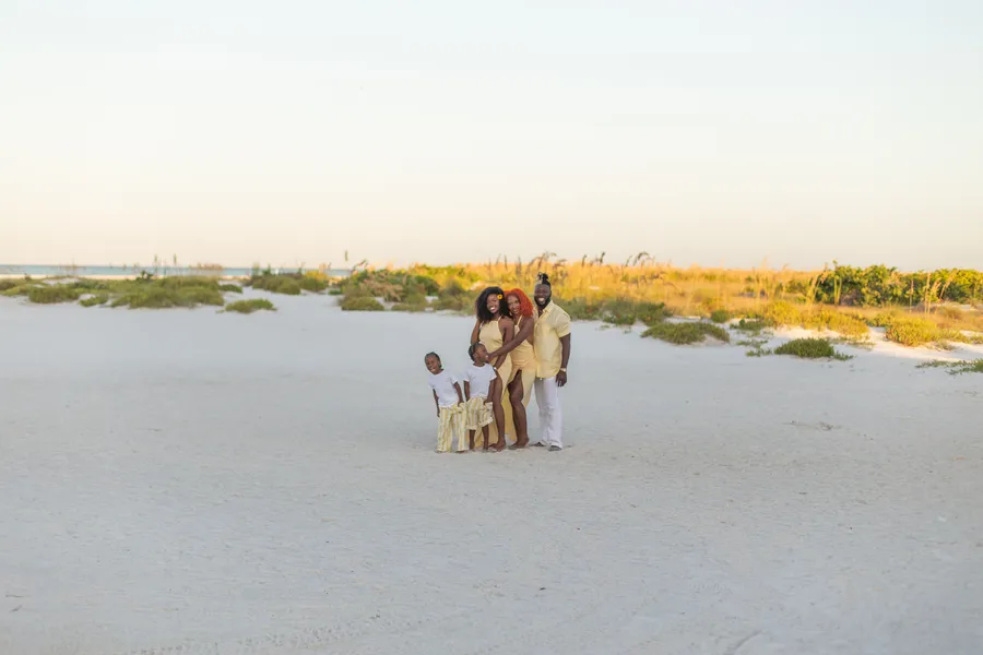Family portrait on a wide white-sand beach at golden hour