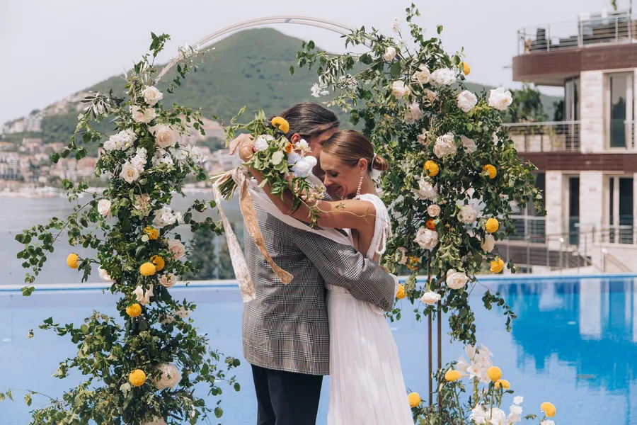 Bride and groom embracing beneath a flowering garden tree