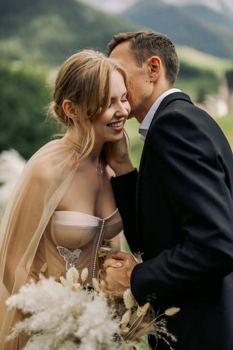 Newlyweds sharing a quiet kiss against a mountain backdrop
