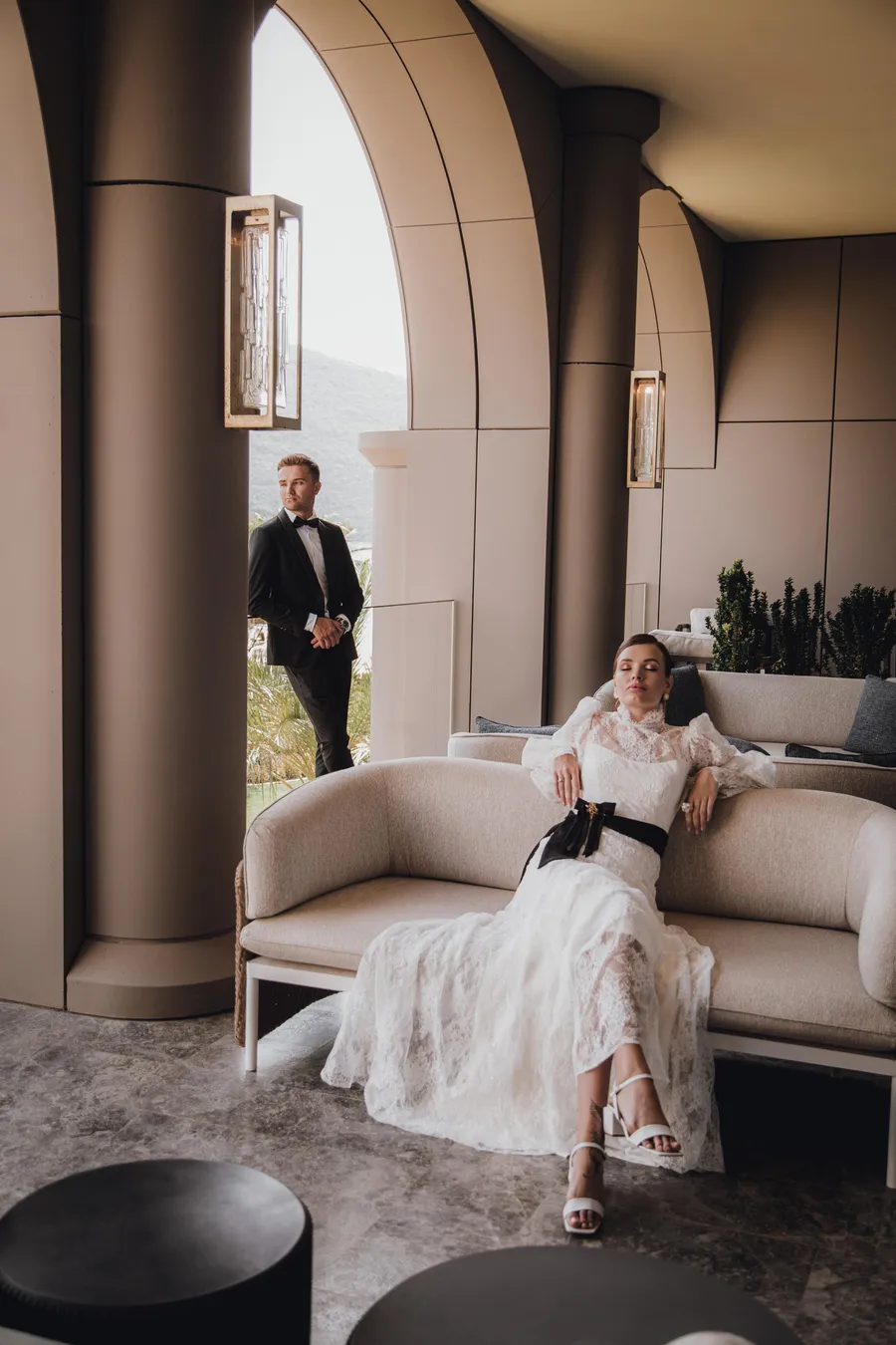 Bride seated in a quiet arched room before her wedding ceremony