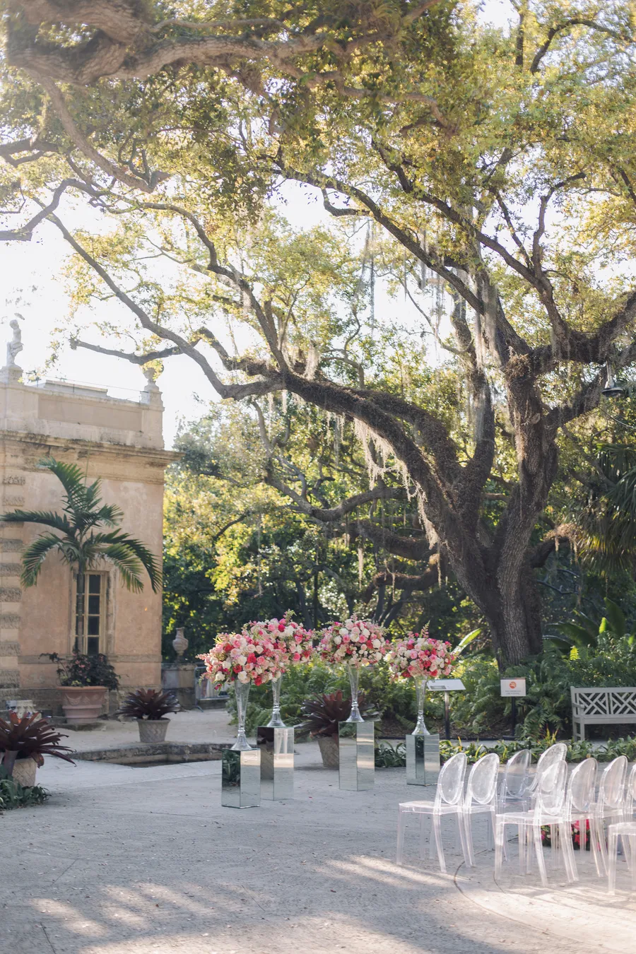Flower-lined garden wedding aisle beneath spreading trees