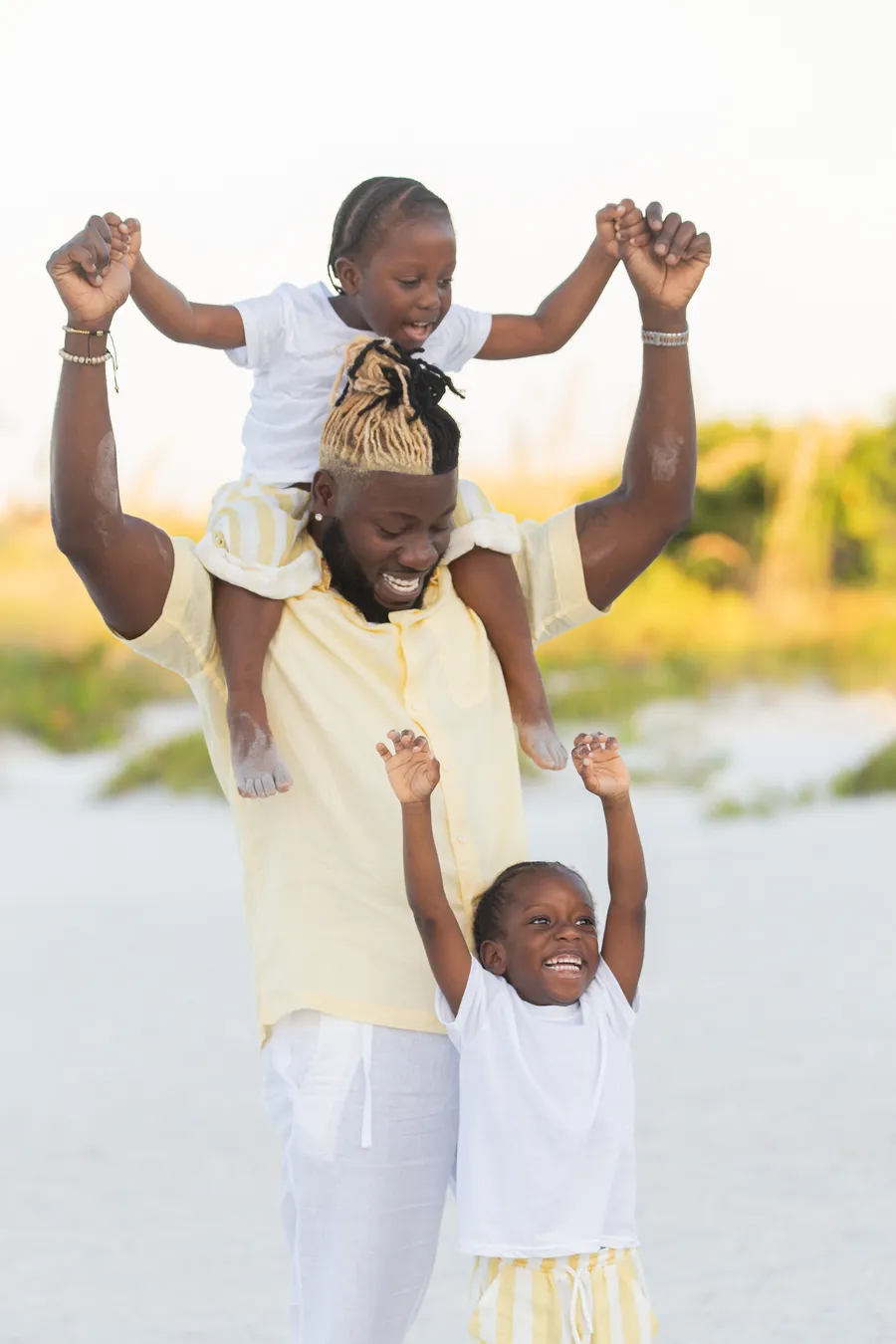 Father carrying his children on his shoulders at the beach