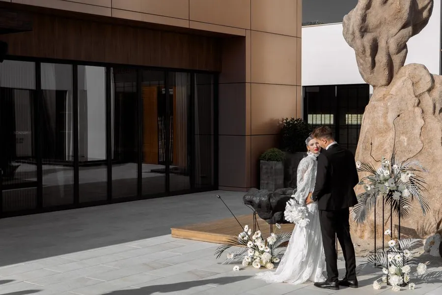 Newlyweds posing beside a monumental stone sculpture