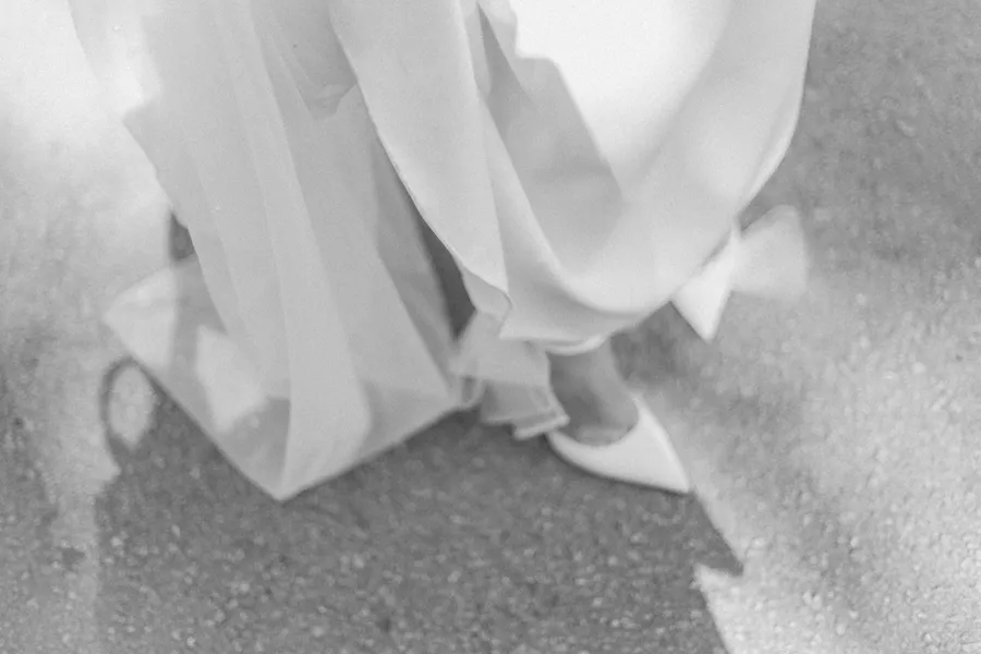 Black-and-white detail of a bride lifting her wedding dress