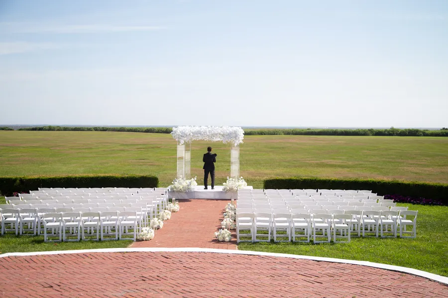 Outdoor ceremony prepared with a white floral arch — David and Katia wedding